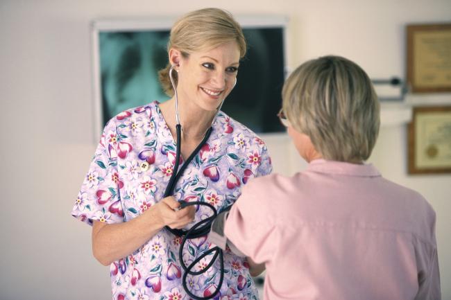 Kvinnelig sykepleier undersøker en pasient