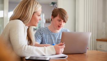 Bilde av dame og mann med downs syndrom foran en pc.