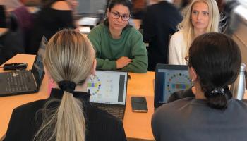 Studenter som sitter i gruppe med pc og diskuterer