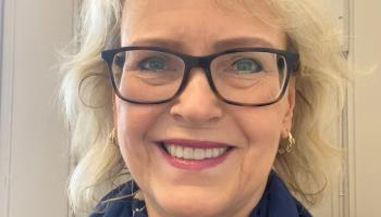 Portrettbilde av blond, smilende dame med briller