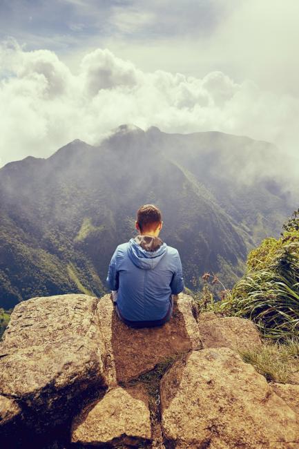 Ung mann sitter alene på fjellet