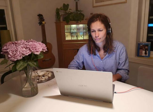 Kvinne sitter foran pc på hjemmekontor. 