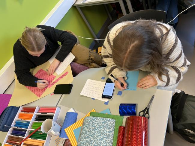 Bilde av to elever sett ovenfra som sitter og tegner ved et bord