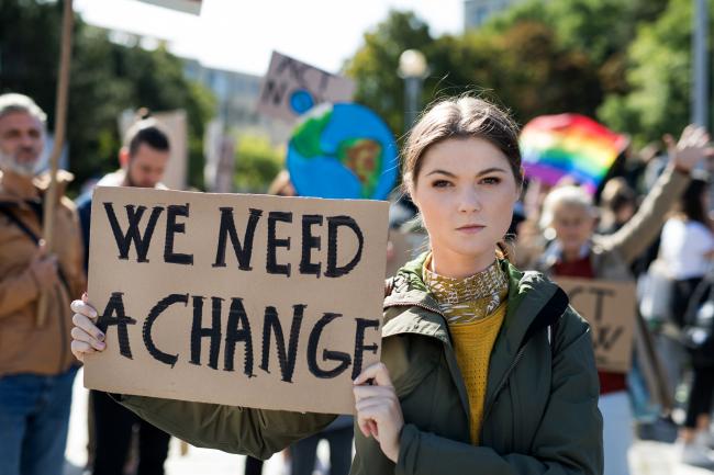 Bilde av ungdom med plakat med teksten "We need a change"