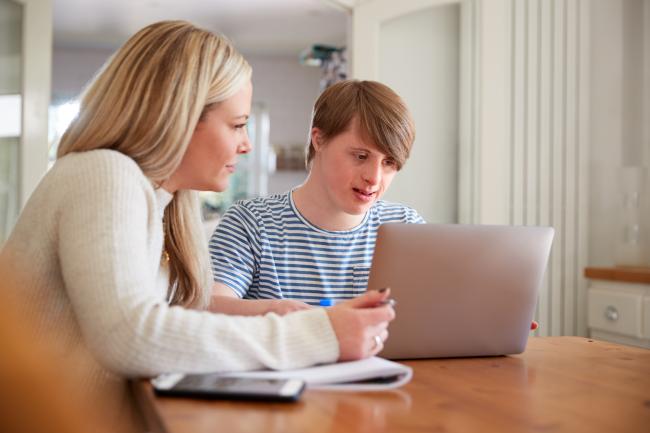 Bilde av dame og mann med downs syndrom foran en pc.
