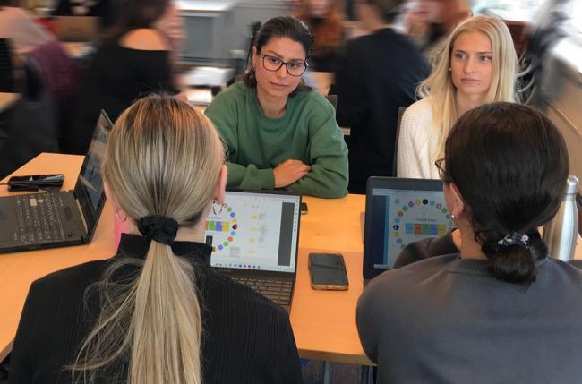 Studenter som sitter i gruppe med pc og diskuterer