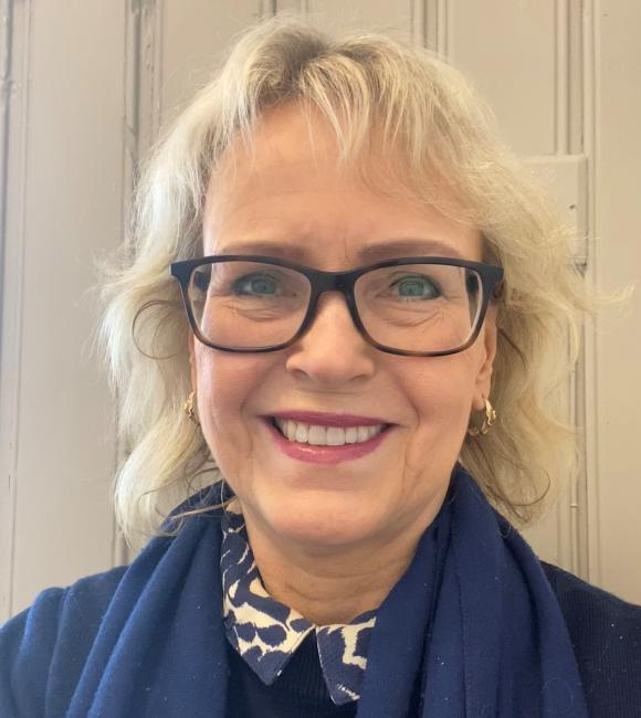 Portrettbilde av blond, smilende dame med briller